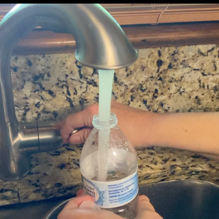 hand holding water bottle and filling with water