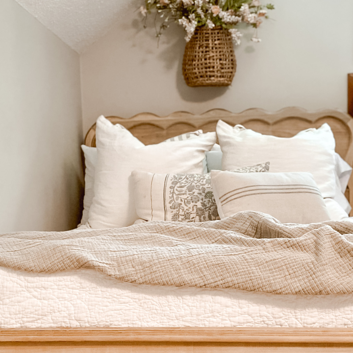 raw wood bed with white quilt and blue pillows