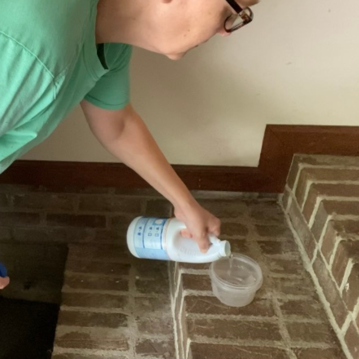 woman pouring bleach into a plastic container