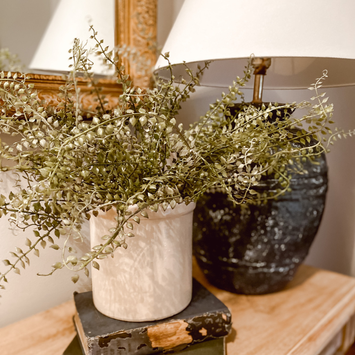 antique crock with greenery beside a navy lamp