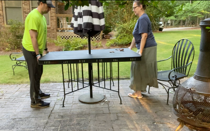 man and woman moving a patio table onto a patio