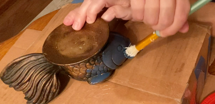 woman painting a fish with blue paint