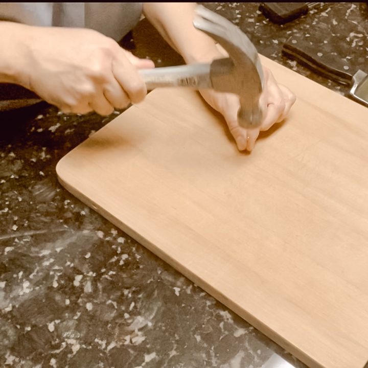 woman nailing a nail into a cutting board