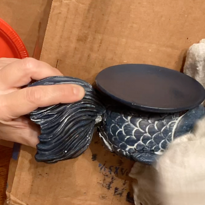 woman putting white wax on thrifted find fish