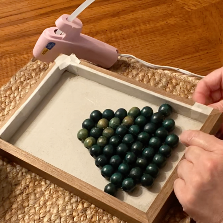 woman adding beads to a canvas