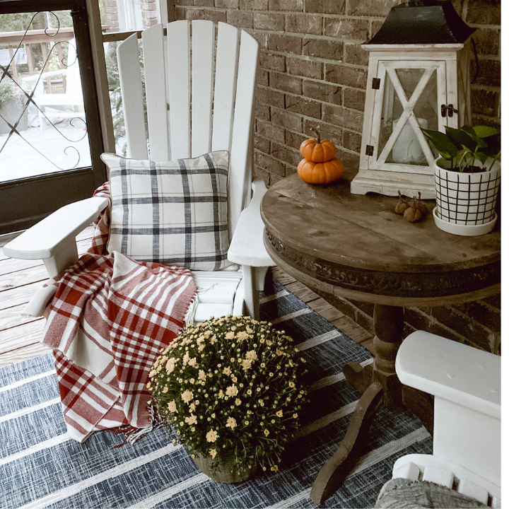 yellow mum beside Adirondack chair with throw blanket and pillow