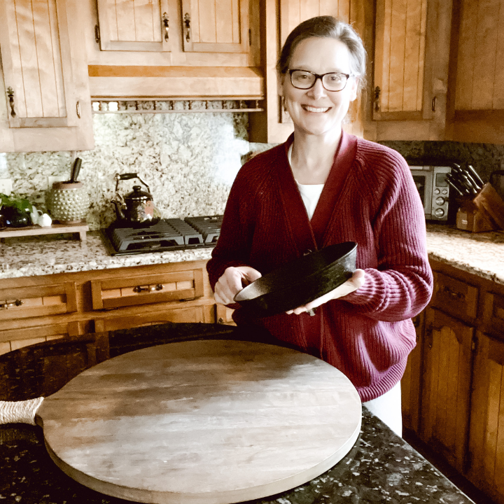 woman standing in kitchen with a cast iron skillet