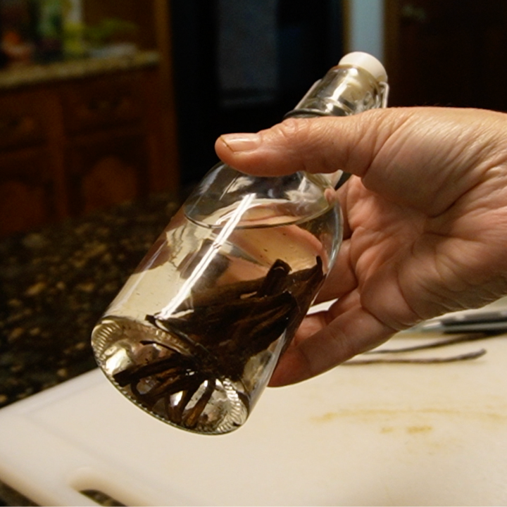 woman shaking the bottle of homemade vanilla extract before storing