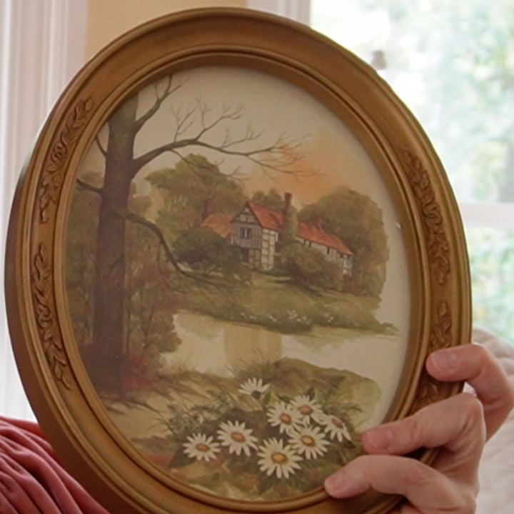 woman holding a gold, round frame with an fall scene